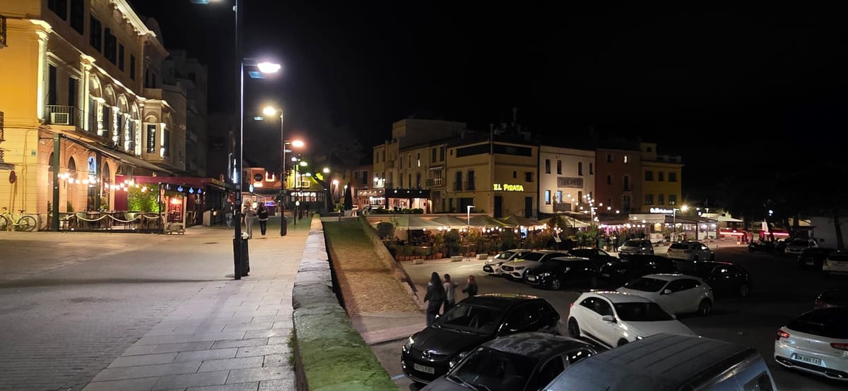 The old town square in Palamós at night, bars and restaurants lit up along the promenade